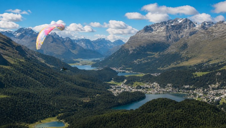 Paraglider above an alpine lake and valley in Engadin